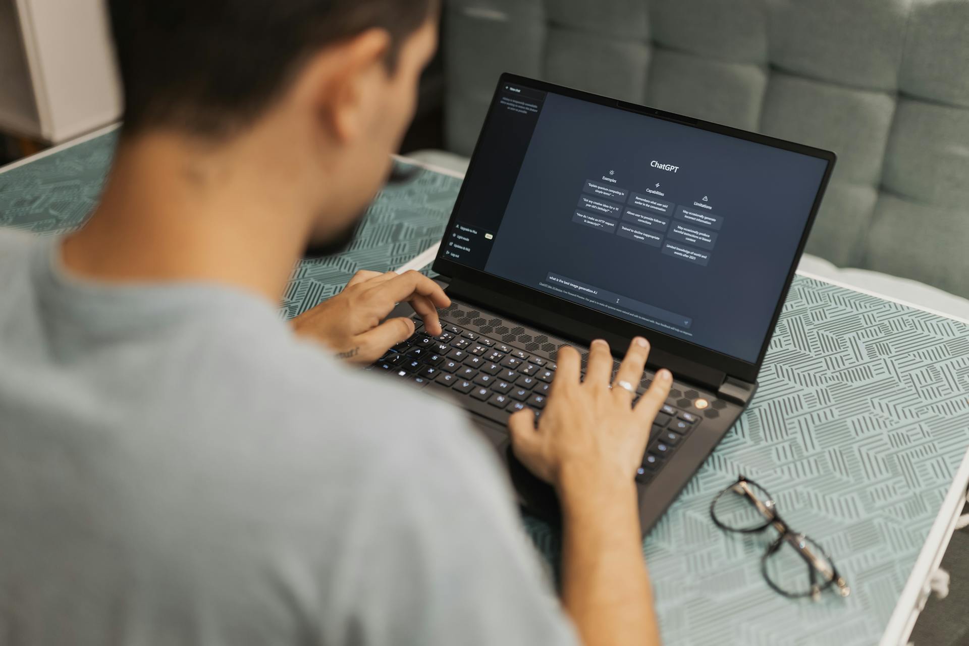A man typing on a laptop computer with the ChatGPT online webpage on the laptop screen