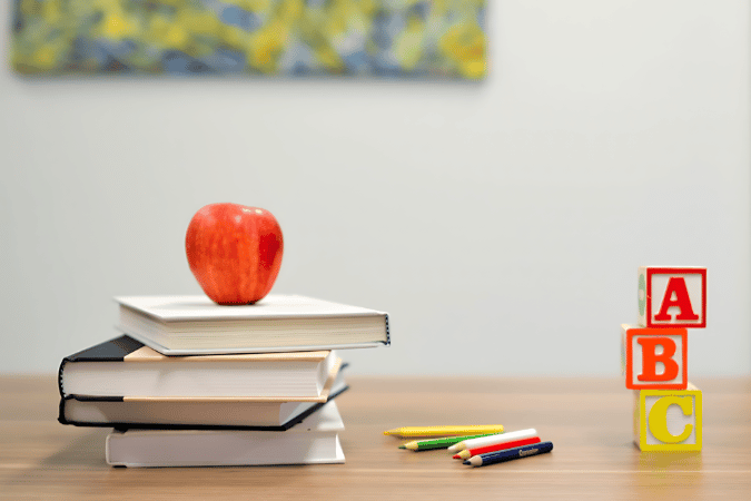 books and apple on a desk with ABC blocks, showcasing AI advantage and artificial intelligence in education